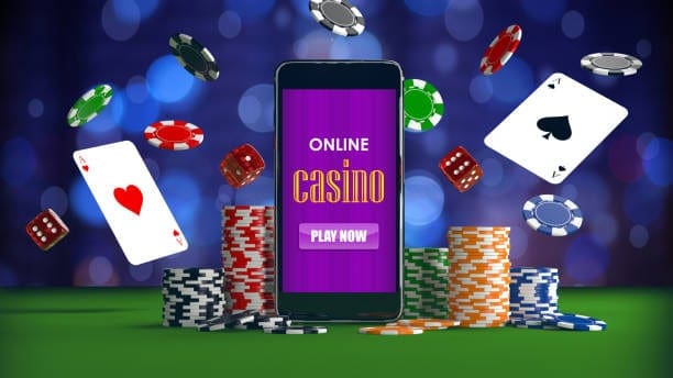 มือถือแสดงคำว่า Online Casino ล้อมรอบด้วยไพ่ ชิป และลูกเต๋าลอยอยู่